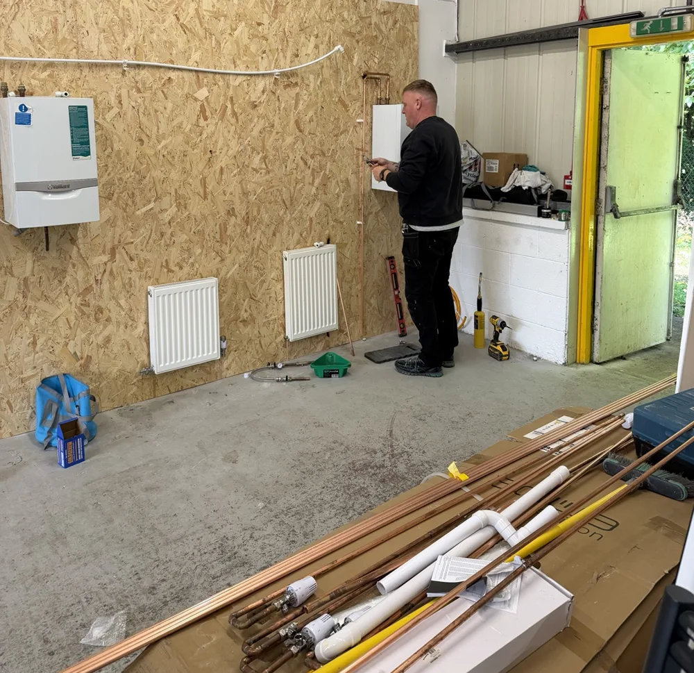 Learner working on copper pipework beside radiators on the training wall