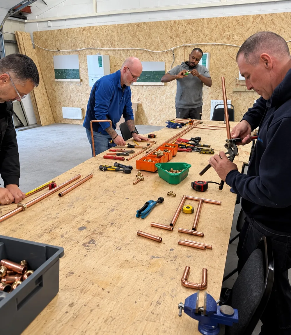 Learners preparing copper pipe and fittings together at the training bench